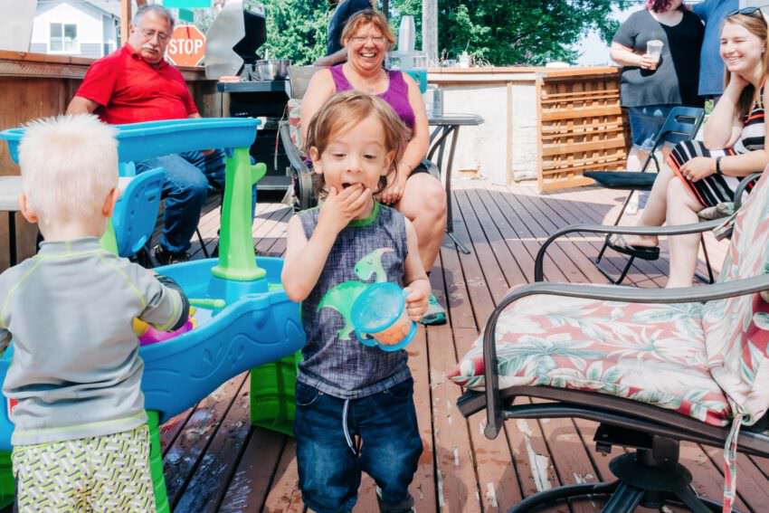 A toddler in a dinosaur tank top eating crackers
