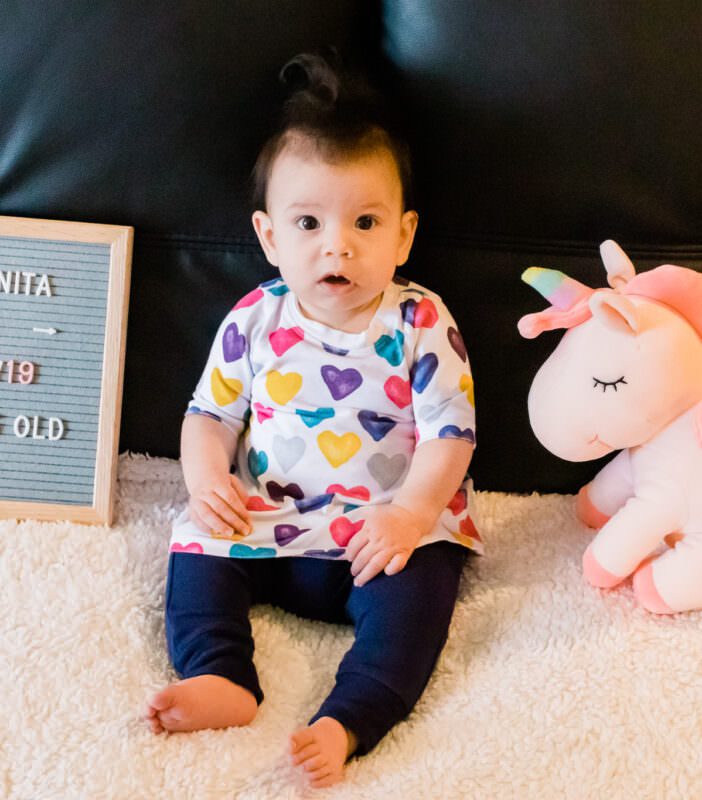 4 month old in colorful heart dress and blue pants